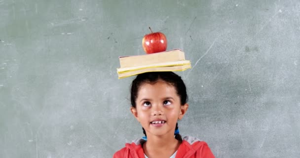 Estudante com uma maçã e livro na cabeça em sala de aula — Vídeo de Stock