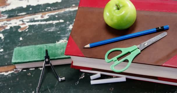 Manzana verde en la pila de libros con útiles escolares — Vídeo de stock