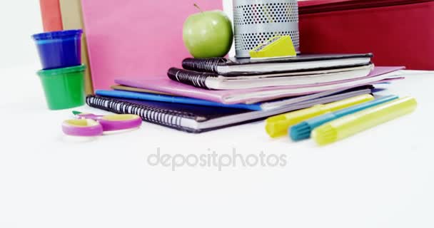 Цветные карандаши в ручке с грудой книг, яблок и канцелярских принадлежностей — стоковое видео