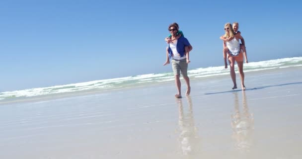 Ouders waardoor meeliften rit naar hun kinderen tijdens het uitvoeren van op de wal op strand — Stockvideo