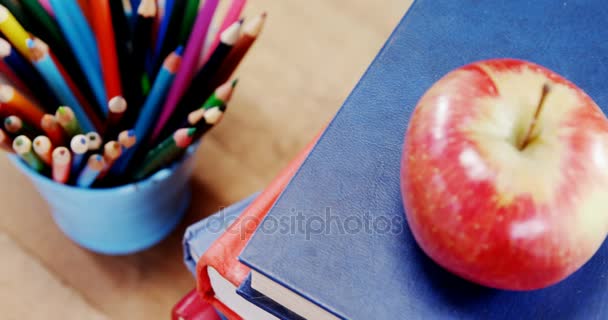 テーブルの上の鉛筆ホルダーと本スタック上のリンゴ — ストック動画
