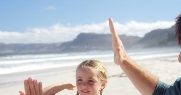 Far och dotter ger hög fem till varandra på stranden — Stockvideo