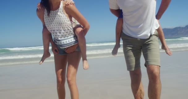 Föräldrar ger piggyback rida till sina barn på stranden — Stockvideo