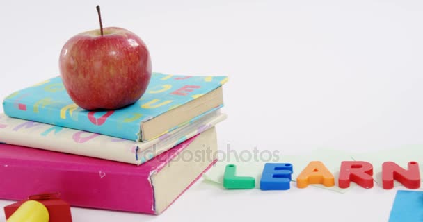 Diverse Schreibwaren und Apfel vor weißem Hintergrund — Stockvideo