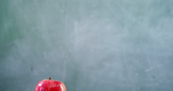 Manzana en la pila de libros con útiles escolares en la mesa — Vídeo de stock