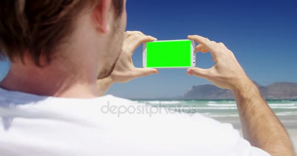 Hombre tomando fotos desde el teléfono móvil en la playa — Vídeos de Stock