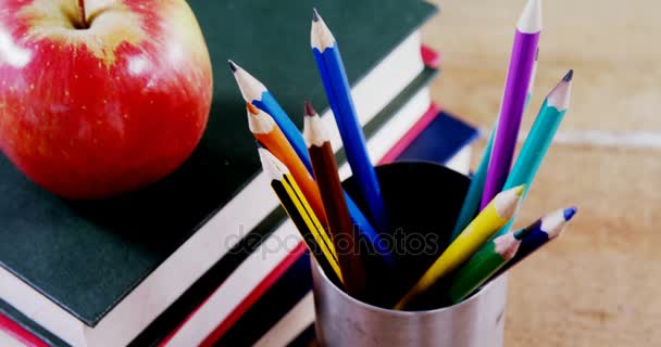 Apple на стопке книг с цветным карандашом на столе — стоковое видео