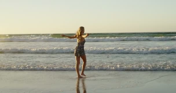 Mulher com braços estendidos brincando na água na praia — Vídeo de Stock