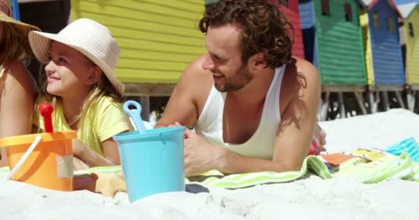 Family lying together on blanket at beach — Stock Video