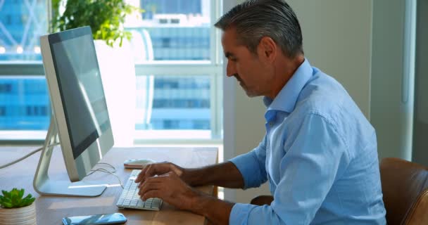 Mężczyzna executive rozmowy na telefon komórkowy, podczas pracy nad komputerem przy biurku — Wideo stockowe