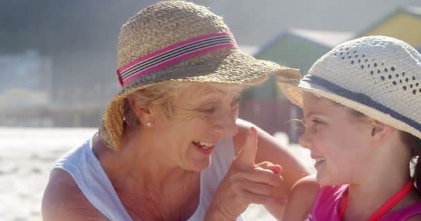 Бабушка и внучка играют друг с другом на пляже — стоковое видео