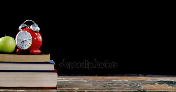 Manzana y despertador en pila de libros con lápices de color en la mesa — Vídeos de Stock