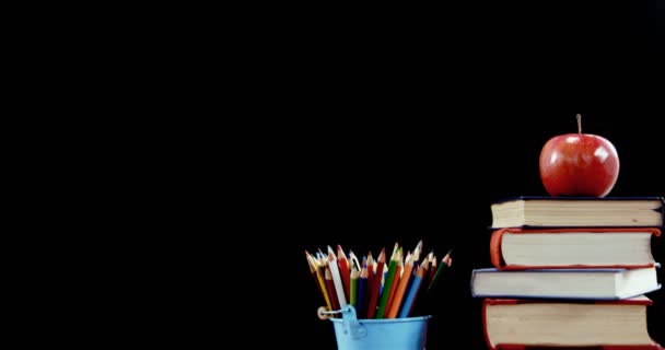 Apple на стопке книг с цветным карандашом на столе — стоковое видео