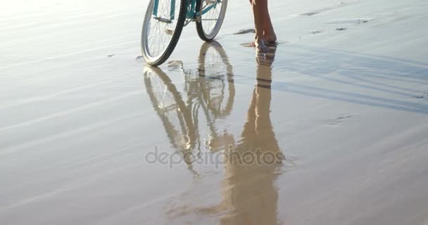 Donna in piedi con la bicicletta in spiaggia — Video Stock