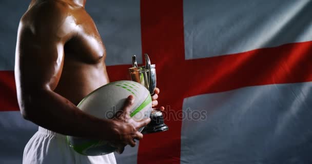 American Football-Spieler mit Trophäe und Rugby-Ball vor schwarzem Hintergrund — Stockvideo