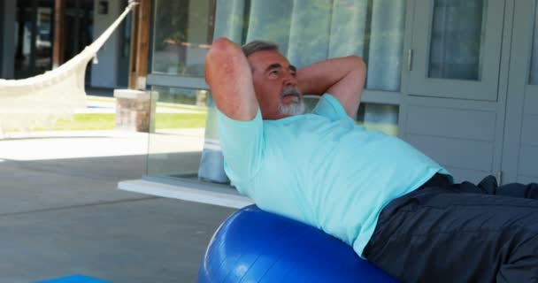 Senior man utövar på fitness boll gör crunches — Stockvideo
