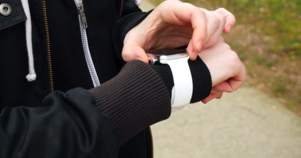 Женщина, использующая умные часы в парке — стоковое видео
