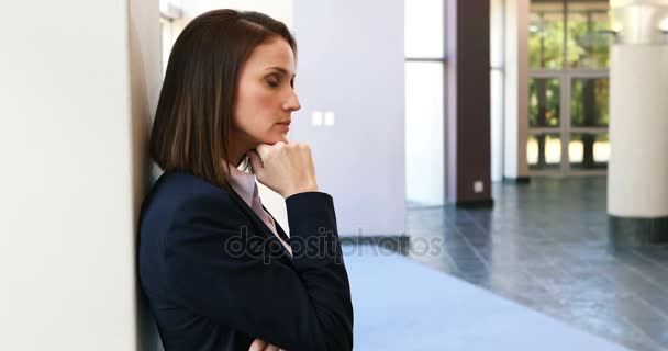 Upset businesswoman leaning against wall — Stock Video