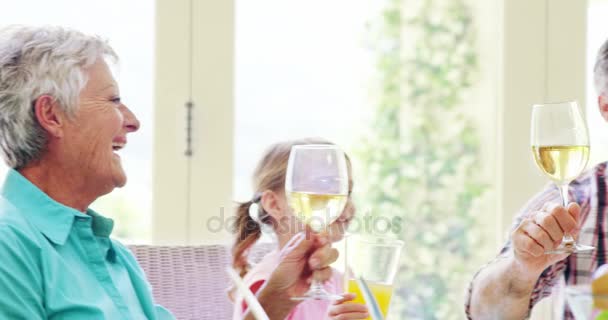 Familia tostando unas copas de vino y jugo en la mesa de comedor — Vídeo de stock
