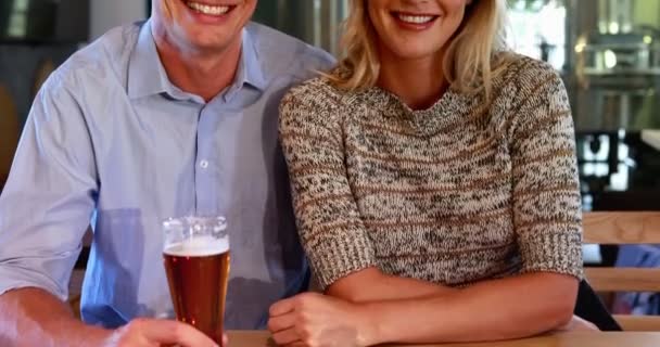 Happy couple holding glasses of beer in bar — Stock Video