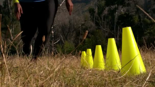 Bassa sezione di donna che corre attraverso i coni di formazione — Video Stock