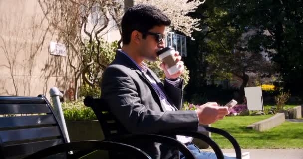 Hombre usando el teléfono móvil mientras toma café — Vídeo de stock