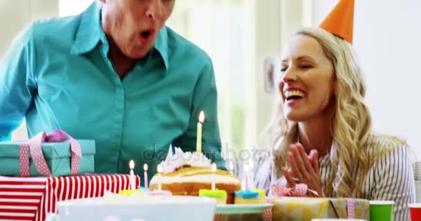 Senior woman blowing out the candles on a birthday cake — Stock Video