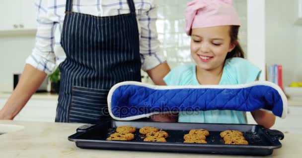 Menina sorridente mantendo bandeja de biscoitos frescos na bancada — Vídeo de Stock