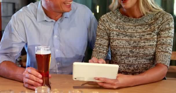 Par med digital surfplatta samtidigt ha öl i baren — Stockvideo
