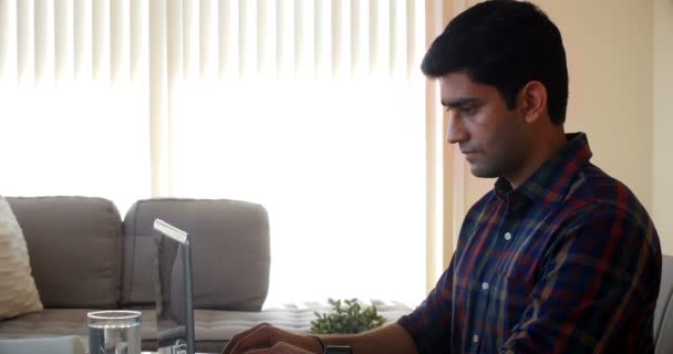 Un bărbat care folosește laptopul în sufragerie — Videoclip de stoc