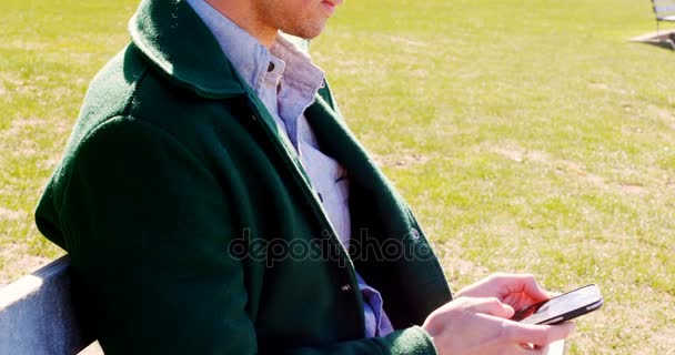 Людина використовує мобільний телефон у парку — стокове відео
