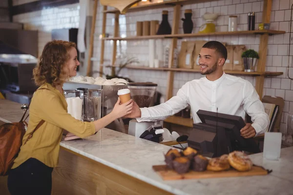 Servitören ger disponibla kaffekopp till kvinna — Stockfoto