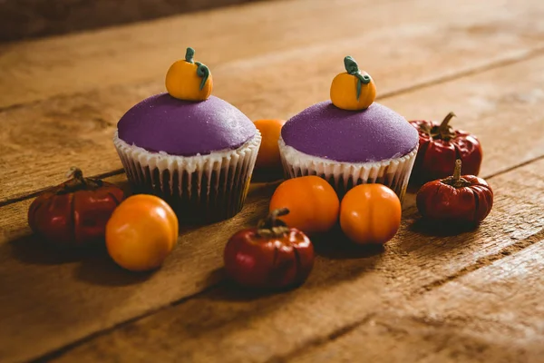 Cup cakes with small pumpkins on wooden table — Stock Photo, Image