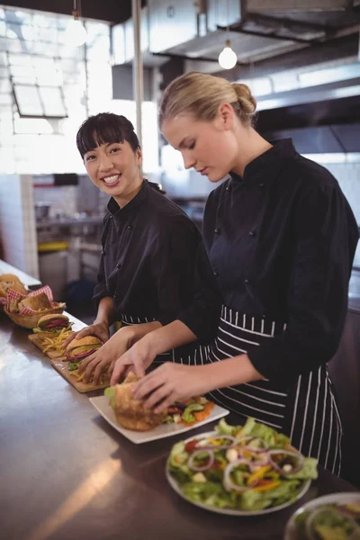 Vrouwelijke chef-kok voor het bereiden van voedsel met collega — Stockfoto