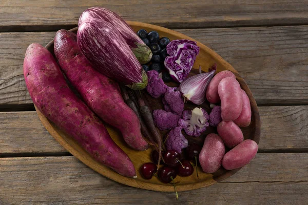 Divers légumes dans un plateau sur une table en bois — Photo