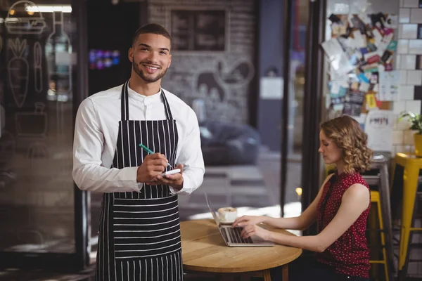 Waiter with notepad by female customer — Stock Photo, Image