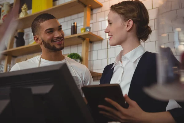 Propietario con mesero sosteniendo la tableta en la cafetería — Foto de Stock