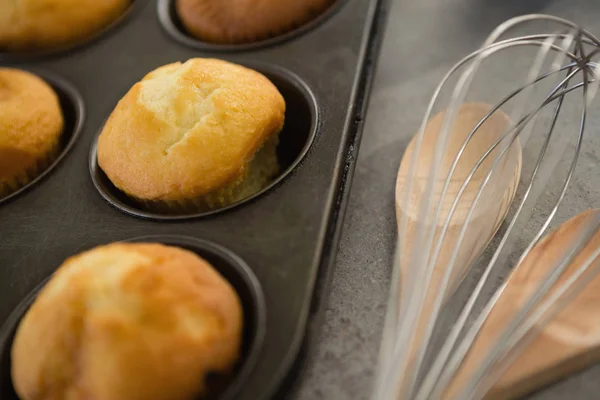 Muffins in tin by wooden spoon and wire whisk — Stock Photo, Image