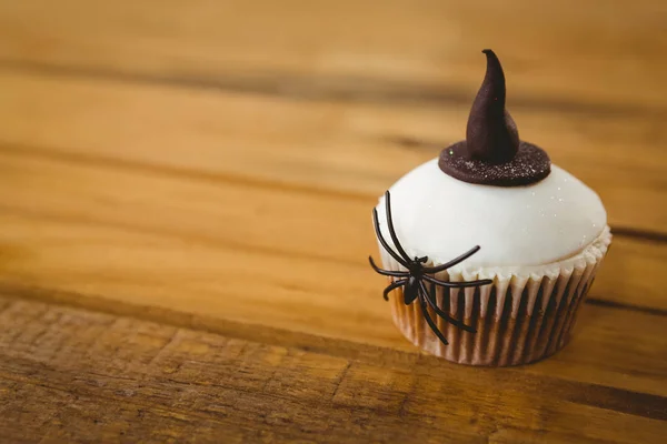 Bolo de xícara com aranha e chapéu de bruxa na mesa — Fotografia de Stock