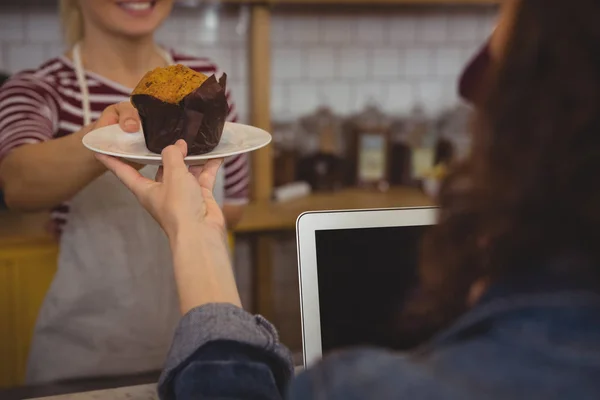 Ägare som serverar muffin till kund — Stockfoto