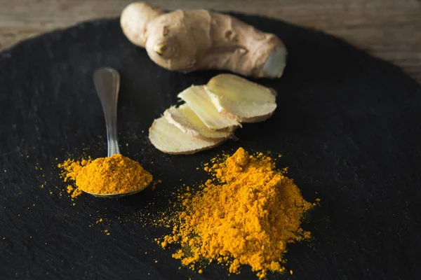 Turmeric powder and ginger on board — Stock Photo, Image