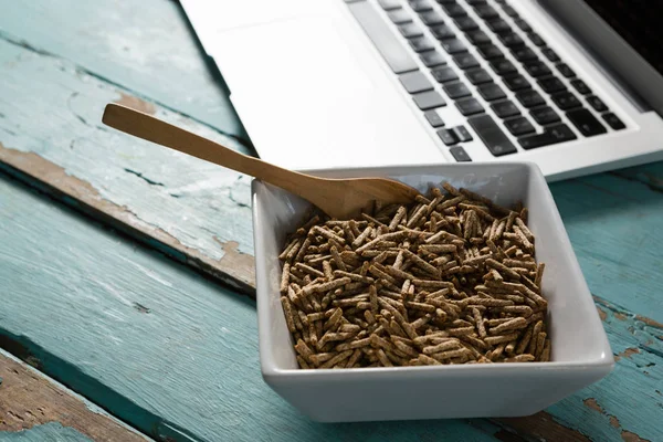 Tigela de farelo de cereais com colher e laptop — Fotografia de Stock