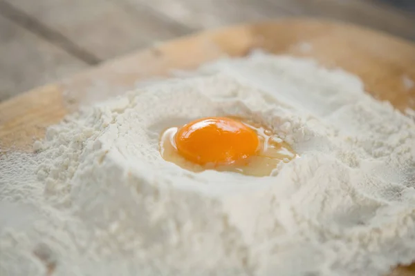 Egg yolk in flour on cutting board — Stock Photo, Image