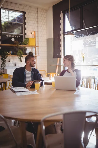 Amici parlando mentre seduto con le tecnologie — Foto Stock