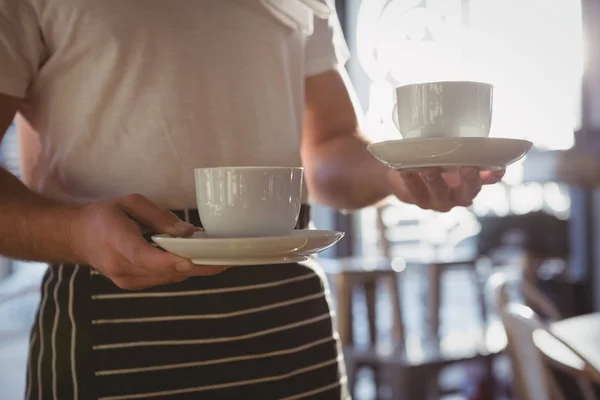 Číšníku, drží šálků kávy v kavárně — Stock fotografie