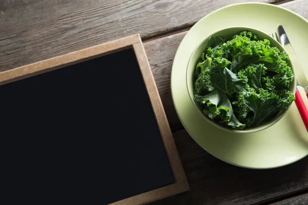 Grönkål i skål på tallrik av blackboard — Stockfoto