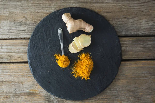 Turmeric powder and ginger on board — Stock Photo, Image