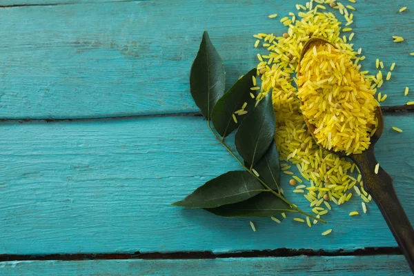 Arroz amarillo orgánico crudo y hojas de curry — Foto de Stock