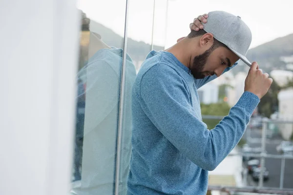 Hombre posando en gorra contra vidrio —  Fotos de Stock