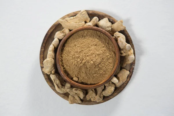 Powder in bowl amidst dried gingers — Stock Photo, Image